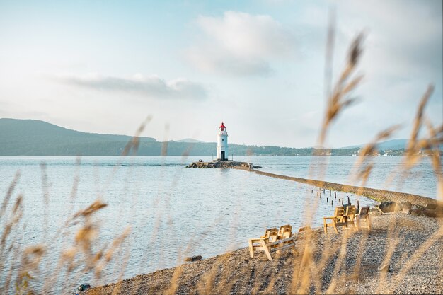 Ein alter Leuchtturm mit rotem Dach an der Küste. Meereslandschaft. Postkarte von der Reise.