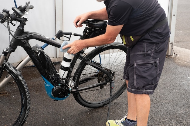 Ein alter Mann wäscht sein Fahrrad und kümmert sich um die Details. Tankstelle. Hochdruckpumpe