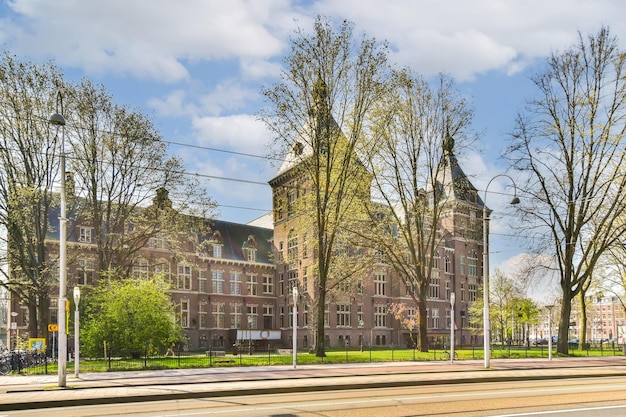 Foto ein altes backsteingebäude im mittleren teil von amsterdam mit bäumen, die die straße säumen, und autos, die an der seite geparkt sind