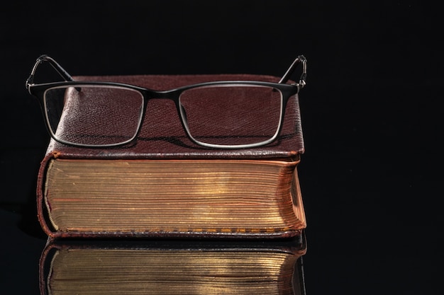 Foto ein altes buch, auf dem eine brille liegt.