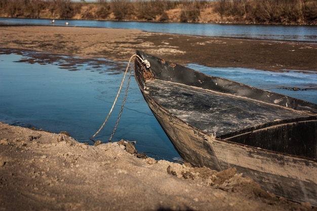 Ein altes Holzboot, das am Ufer des Wassers in Italien aufgegeben wurde