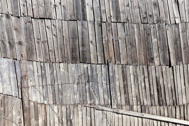 Ein altes Holzhaus aus Holz und Brettern, eine große und hohe Mauer auf vielen Ebenen