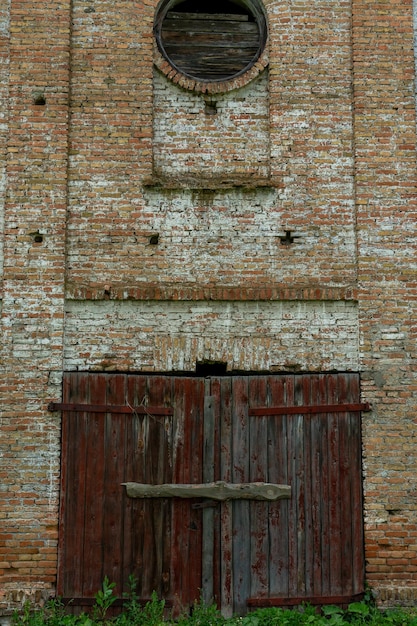 Ein altes Nichtwohngebäude aus Backstein Ein altes historisches Gebäude Ungewöhnliche Rundbogenfenster und große Holztore in einer alten Synagoge