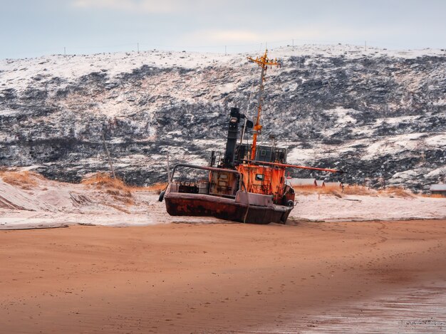 Ein altes rostiges Fischerboot, das von einem Sturm am Ufer verlassen wurde