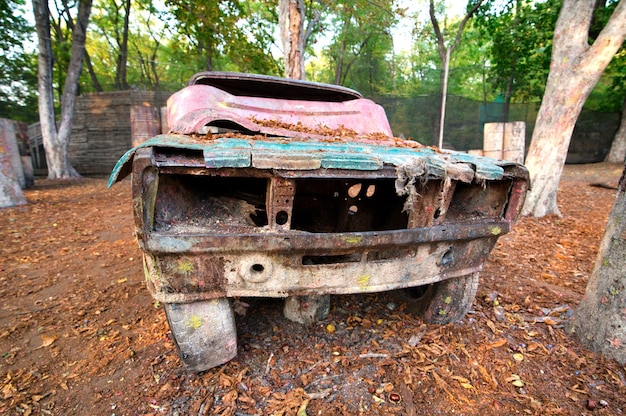 Ein altes rostiges und verlassenes Auto auf einer Paintball-Basis, hinter dem sich Spieler verstecken, die vom Spiel begeistert sind