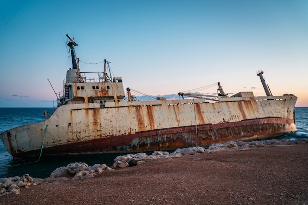 Ein altes verrostetes Schiff gestrandet steht an der Küste.