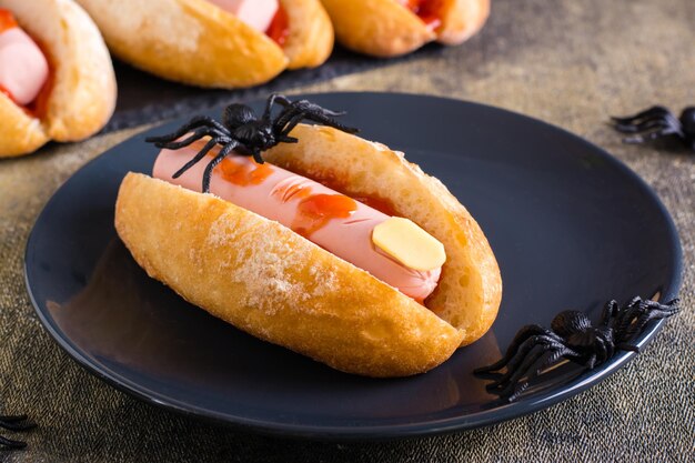 Ein amputierter Wurstfinger in Ketchup in einem Brötchen auf einem Teller Halloween-Rezept