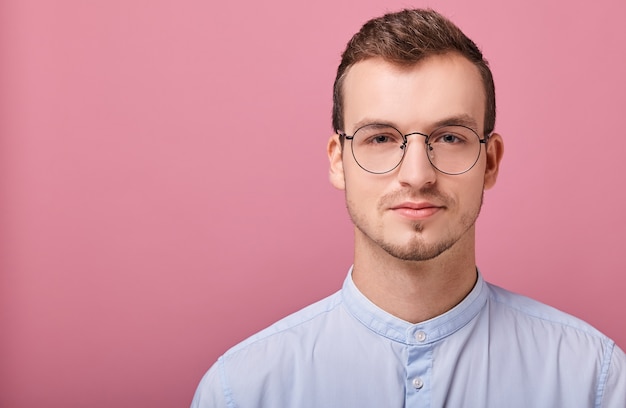 Ein anständiger Angestellter im blauen Hemd und in der Brille steht auf Rosa