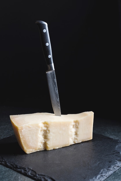 Ein appetitlicher fester Käse auf einem schwarzen Teller mit Messer