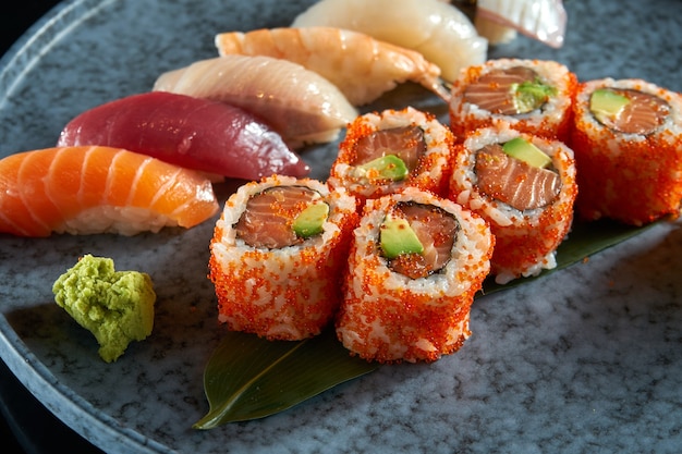 Ein appetitliches Sushi-Set bestehend aus verschiedenen Nigiri und Uramaki mit Lachs, Avocado und Tobiko-Kaviar. Traditionelle japanische Küche. Lebensmittellieferservice. Isoliert auf schwarz