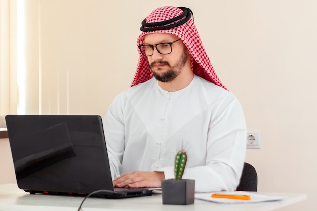 Ein Araber, ein Geschäftsmann, ein Scheich arbeitet an einem Laptop. Investitionen, Geschäfte, Arbeiten über das Internet, Online-Verträge.