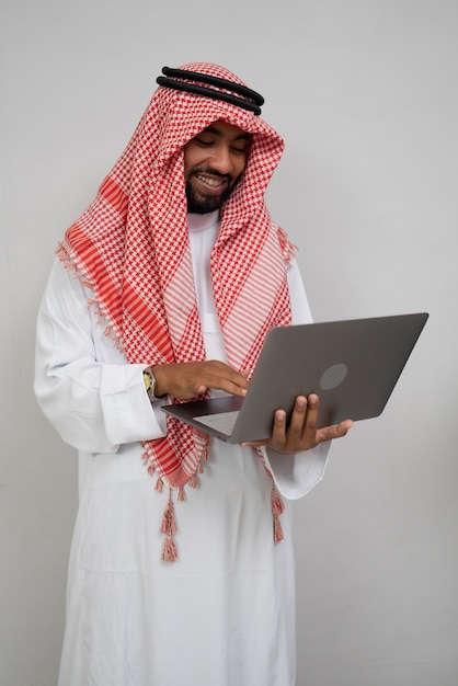 Ein Araber mit Turban, der lächelt, während er einen Laptop benutzt