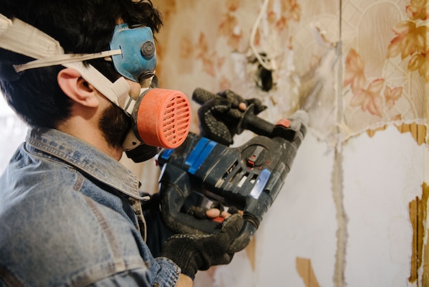 Ein Arbeiter bohrt eine Wand mit einem Perforator. Reparatur in der Wohnung