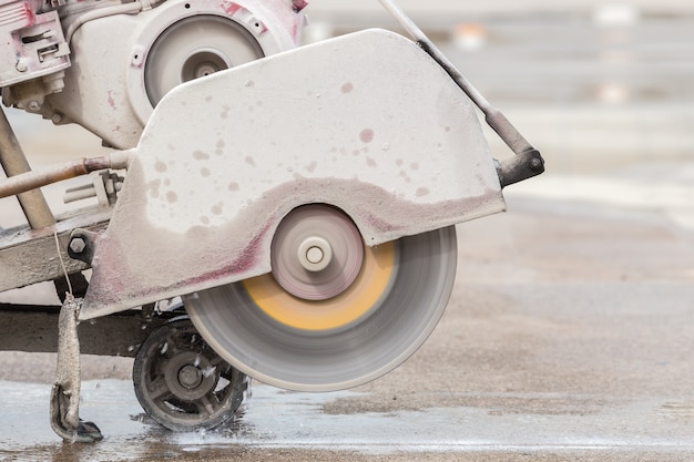 Ein Arbeiter, der Betonstraße mit Diamantsägeblattmaschine schneidet