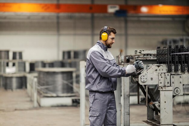 Ein Arbeiter der Schwerindustrie in Schutzuniform verwaltet eine Metallverarbeitungsmaschine