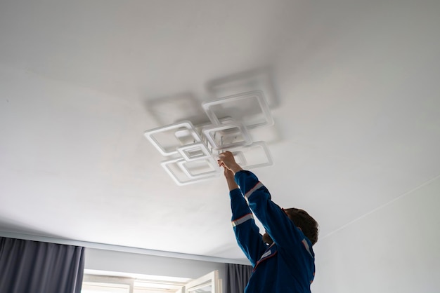 Ein Arbeiter in blauer Uniform, der das LED-Licht zu Hause repariert