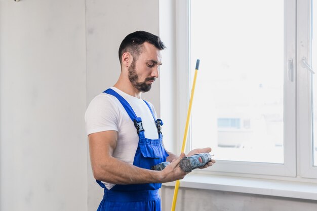 Ein Arbeiter in einem blauen Overall hält ein Maßband in der Hand