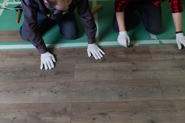 Ein Arbeiter klopft mit den Händen auf ein Laminat, das die Platten mit einem Schloss-Klick verbindet