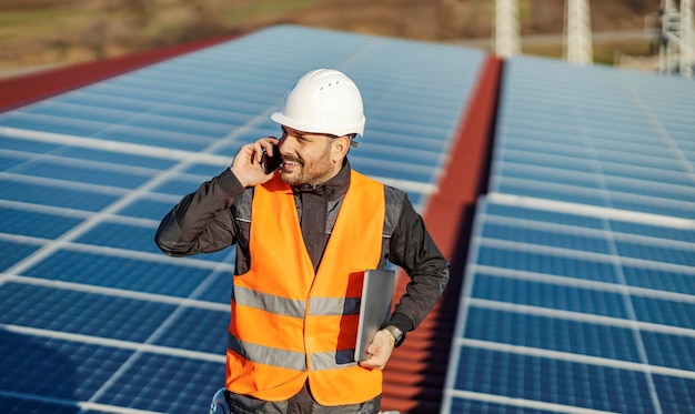 Ein Arbeiter telefoniert mit seinem Chef, nachdem er Solarzellen auf dem Dach getestet hat