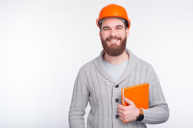 Ein Architekt, der ein orange Buch auf weißem Hintergrund hält.