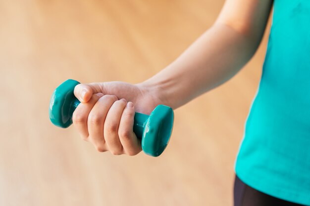 Ein Arm einer jungen Frau, die eine Hantel hält