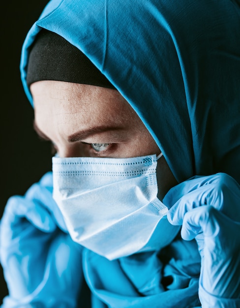 Ein Arzt, eine muslimische Frau in einem Hijab und ein medizinischer Schutzverband