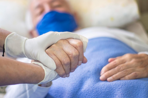 Ein Arzt hält die Hand eines Patienten in einem Krankenhausbett.