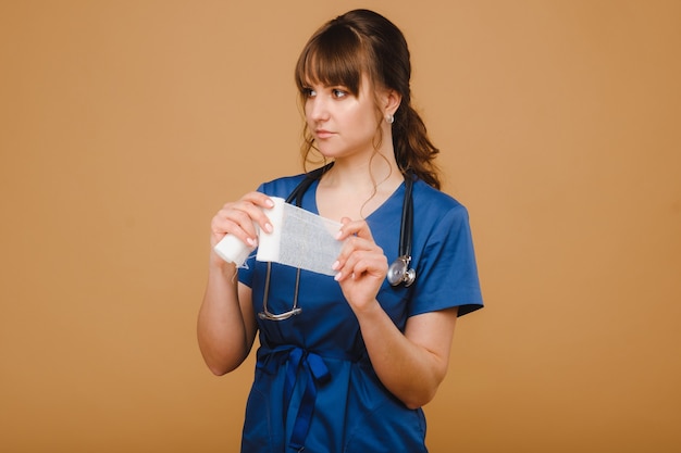 Ein Arzt in einem blauen Laborkittel hält eine Rolle Mullbinden hoch, um Wunden zu verbinden