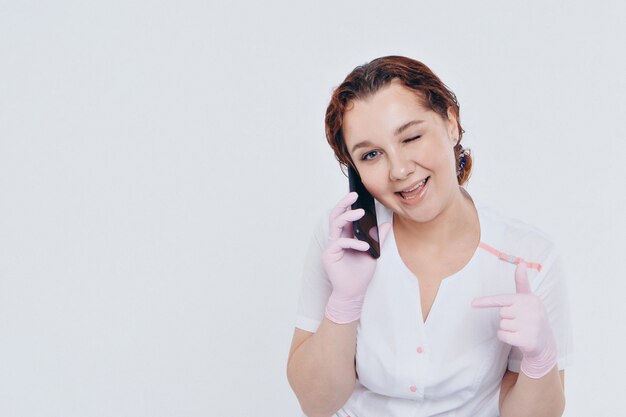 Ein Arzt in Handschuhen telefoniert auf weißem Grund.