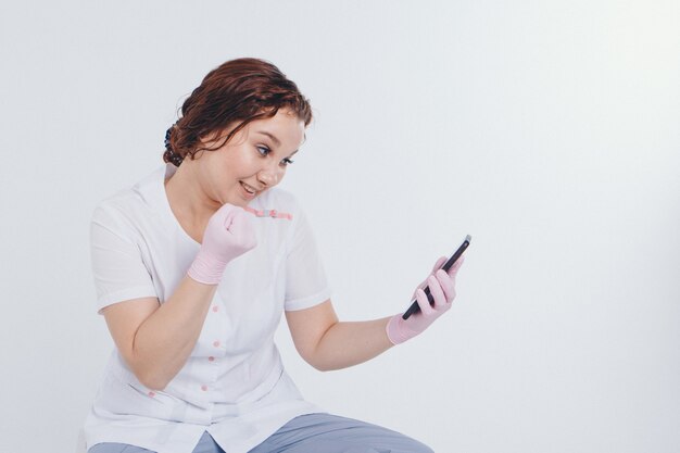 Ein Arzt in Handschuhen telefoniert auf weißem Grund.