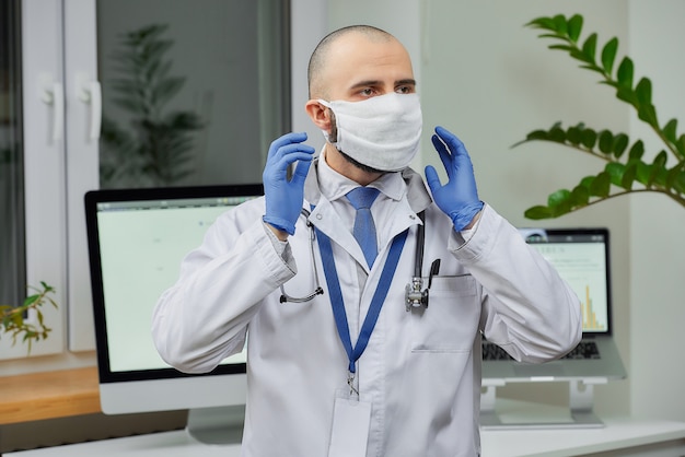 Ein Arzt korrigiert eine schützende Gesichtsmaske, um die Ausbreitung des Coronavirus in seinem Büro zu vermeiden.