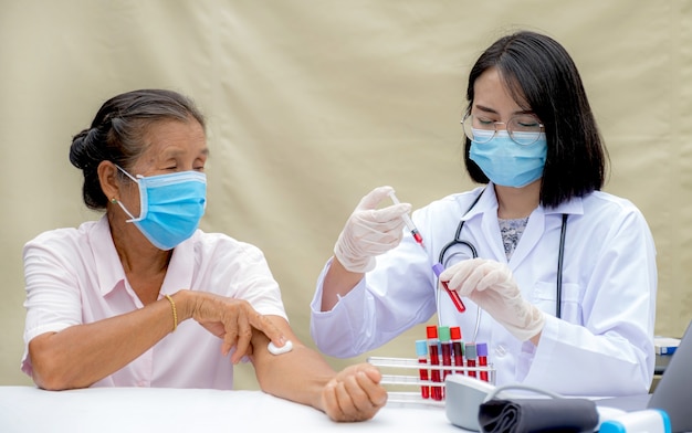 Ein Arzt mit einer Spritze und einer Blutröhrchenprobe zur Analyse und zum Testen von Viruserkrankungen im Labor von älteren Patienten. Diese Forschung ist Plasmabiomedizin für die diagnostische medizinische Versorgung.