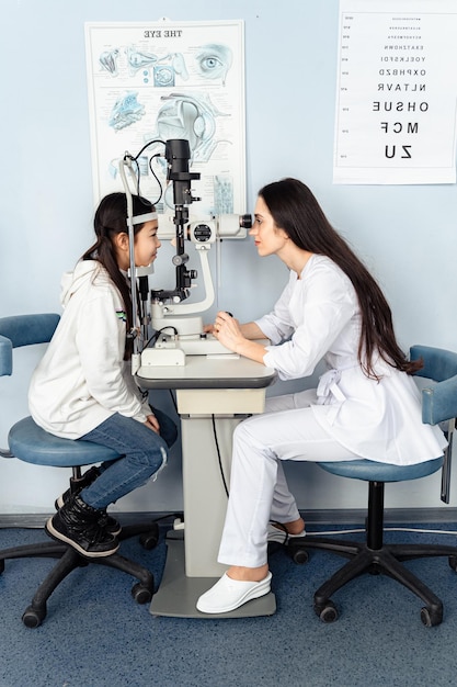 Ein Arzt und ein Mädchen betrachten ein Mikroskop und schauen sich eine Augenuntersuchung mit einem Arzt an