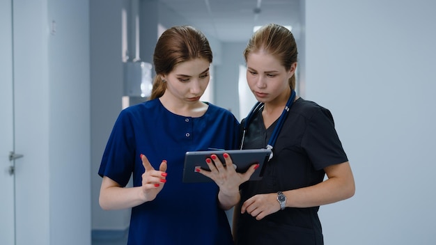 Ein Arzt und eine Krankenschwester stehen in der Klinik und schauen auf den Tablet-Bildschirm und besprechen die Diagnose des Patienten. Panoramafoto