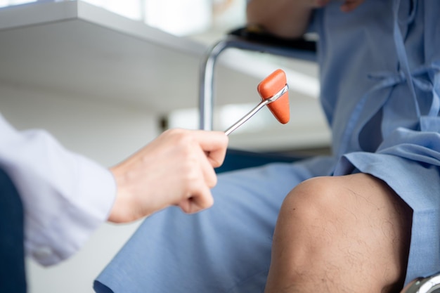 Ein Arzt verwendet einen Reflexhammer, um das Kniegelenk eines Patienten zu bewerten