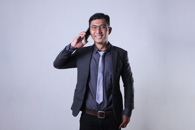 Ein asiatischer Geschäftsmann spricht mit einem selbstbewussten Gesichtsausdruck am Telefon