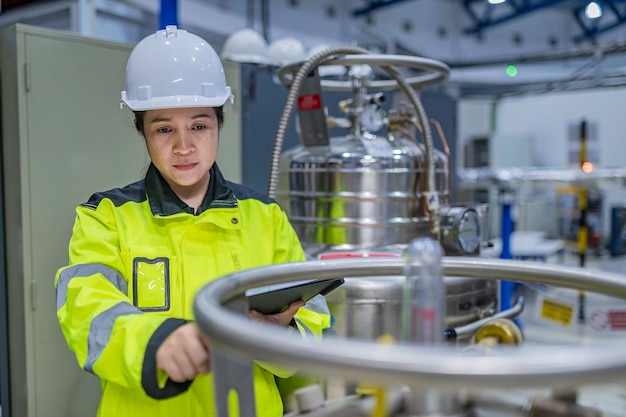 Ein asiatischer Ingenieur arbeitet in der Operationshalle. Die Thailänder tragen Helme. Er arbeitete fleißig und geduldig. Er überprüfte den Ventilregulator am Wasserstoffbehälter.