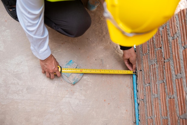 Ein asiatischer Ingenieur mit Schutzhelm überprüft die Baustelle und analysiert