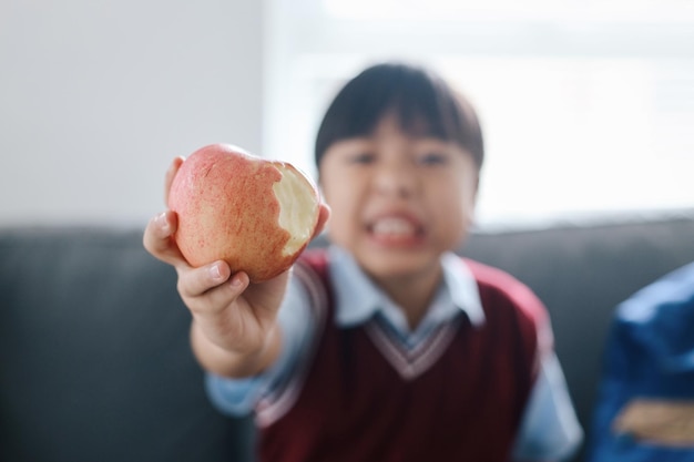 Ein asiatischer Junge isst Äpfel, ein gesundes Schulfrühstück für ein Kind.