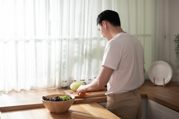 Ein asiatischer junger Mann, der das Frühstück mit gesundem Essen zubereitet