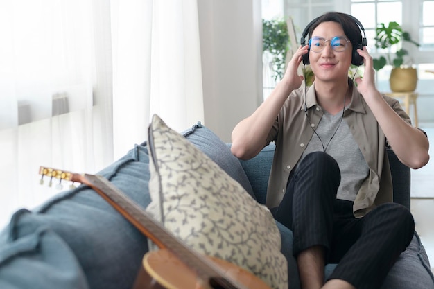 Ein asiatischer Mann hört Musik im Wohnzimmer