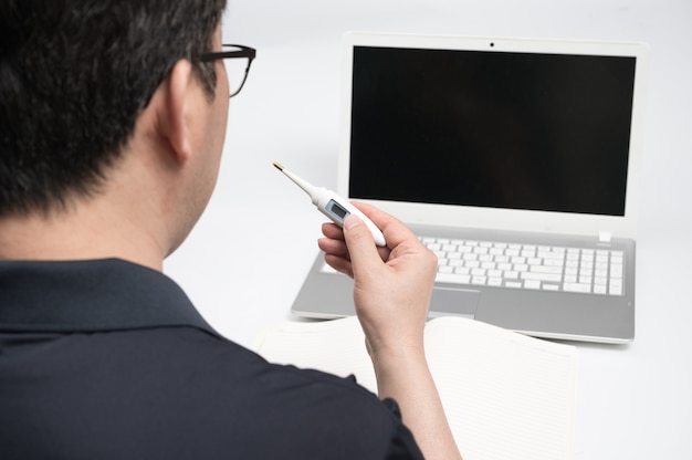 Ein asiatischer Mann mittleren Alters, der einen Laptop benutzt, um einen Arzt für Telemedizin zu konsultieren. Telegesundheitskonzept.