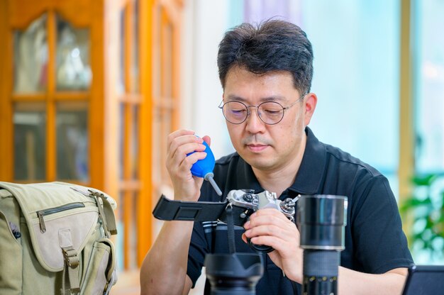 Ein asiatischer Mann mittleren Alters, dessen Hobby eine Spiegelreflexkamera mit 35 mm / 135 mm ist