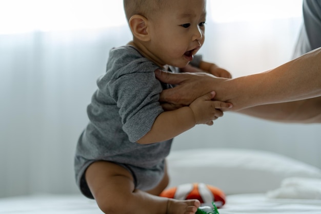 Ein asiatisches Baby vertraut der Hand seines Vaters, um Vater und Sohn aufzustehen und Zeit miteinander zu verbringen