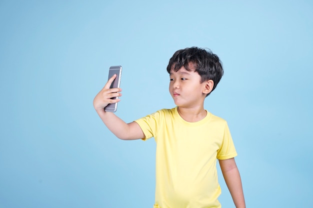 Ein asiatisches hübsches kleines Kind, das süchtig nach seinem mobilen Smartphone ist