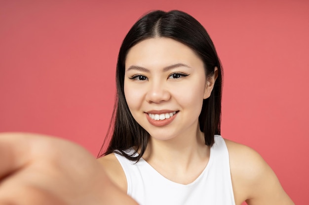 Ein asiatisches Mädchen hält die Kamera des Betrachters mit der Hand