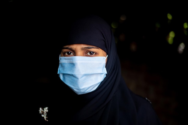 Ein asiatisches muslimisches Mädchen, das eine chirurgische Maske zum Schutz vor Coronavirus trägt Hijab-Frau, die eine Maske zur Sicherheit trägt Hochformat