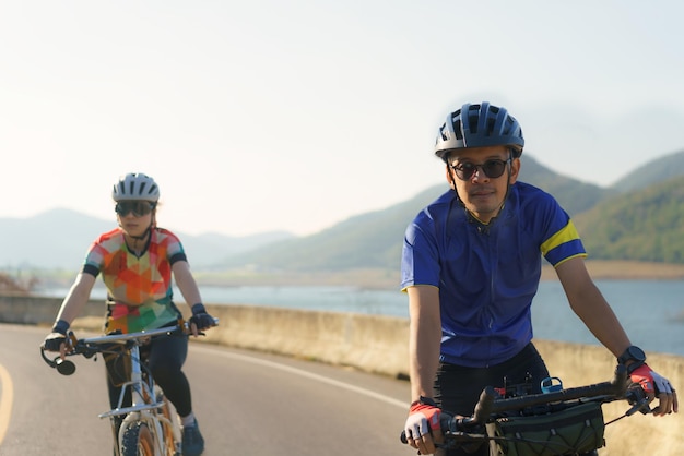 Ein asiatisches Radfahrerpaar fährt morgens zusammen um den See herum.