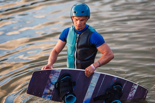 Ein Athlet führt bei Sonnenuntergang einen Trick im Wasserpark vor. Wakeboard-Fahrer