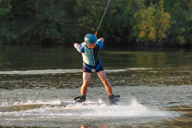 Ein Athlet führt bei Sonnenuntergang einen Trick im Wasserpark vor. Wakeboard-Fahrer